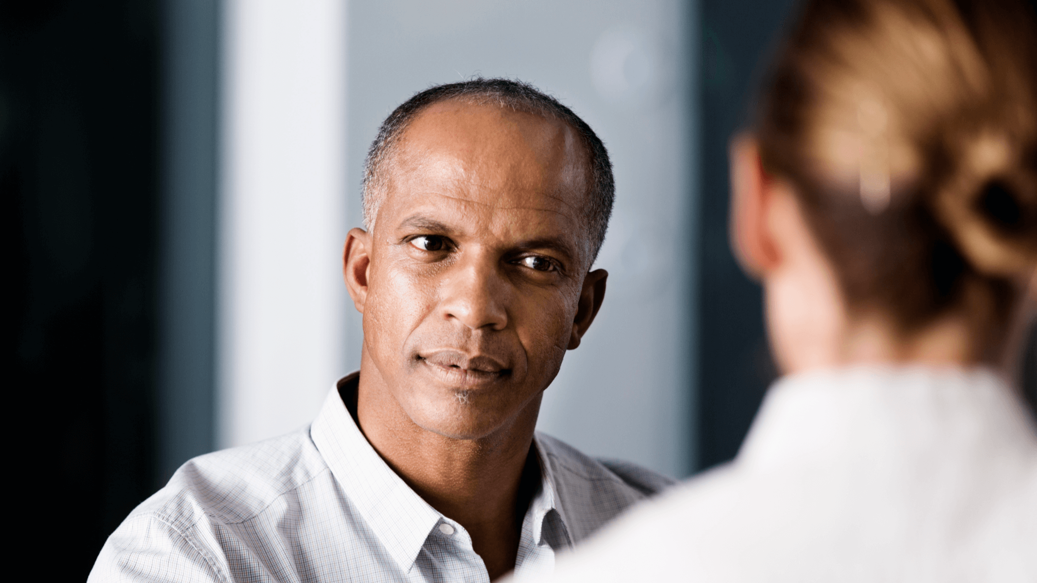 Close-up of a middle-aged African American man in a thoughtful conversation with a healthcare professional, suggesting a doctor-patient discussion about prostate health and screening.